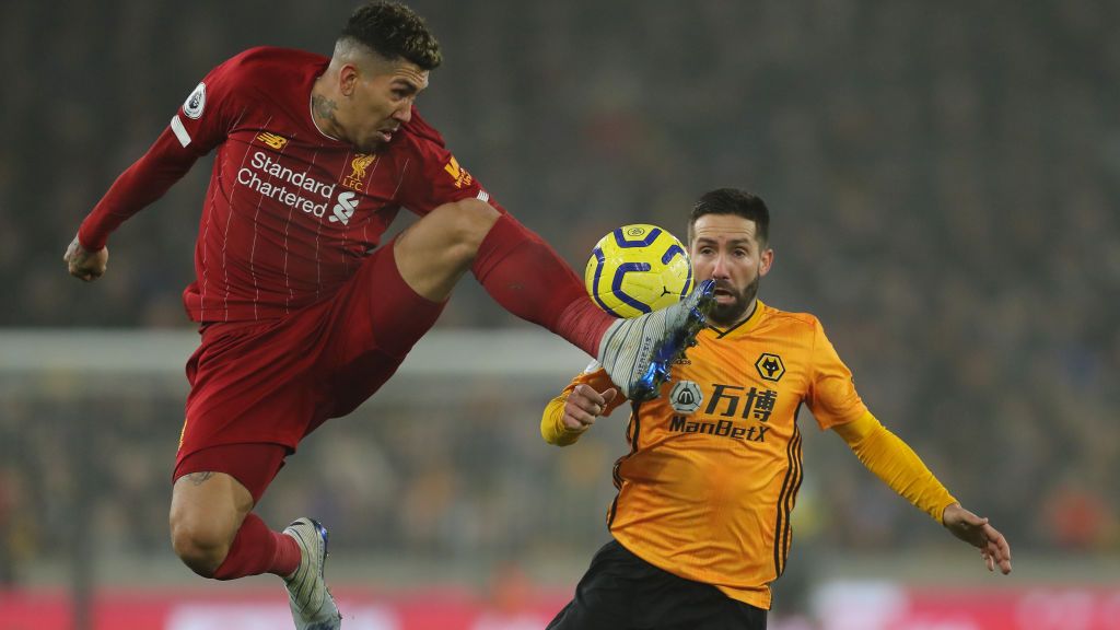 Striker Liverpool, Roberto Firmino, saat menahan bola di depan pemain Wolves, Joao Moutinho Copyright: © Matthew Ashton - AMA/Getty Images