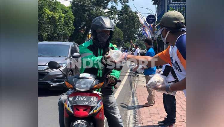 Klub Liga 1 Arema FC turut menggelar aksi sosial dengan membagikan bantuan konsumsi bagi masyarakat Kota Malang yang terdampak pandemi virus corona. Copyright: © Ian Setiawan/INDOSPORT