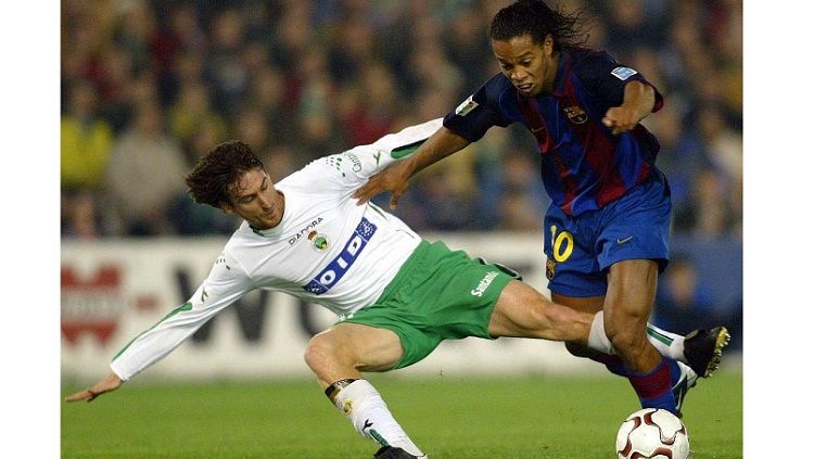 Bintang Barcelona, Ronaldinho, berupaya melewati pemain Racing Santander dalam pertandingan LaLiga Spanyol, 4 Januari 2004. Copyright: © AFP