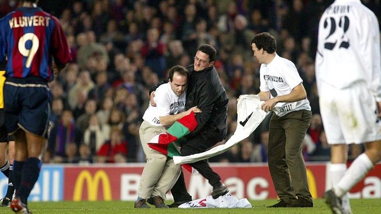 Penyusup lapangan ditangkap petugas dalam pertandingan LaLiga Spanyol antara Barcelona kontra Real Madrid, 16 Maret 2002. Copyright: © Firo Foto