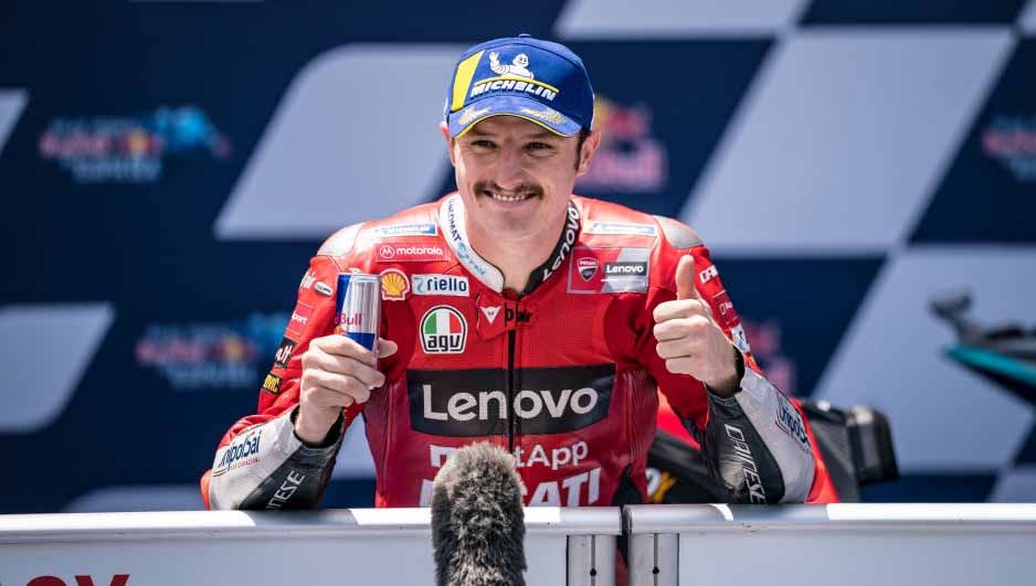 Pembalap asal Australia, Jack Miller, memberikan sarung tangannya pada seorang penggemar setelah ia finis ketiga di MotoGP Jerman pada akhir pekan (19/06/22). Copyright: © Steve Wobser/Getty Images