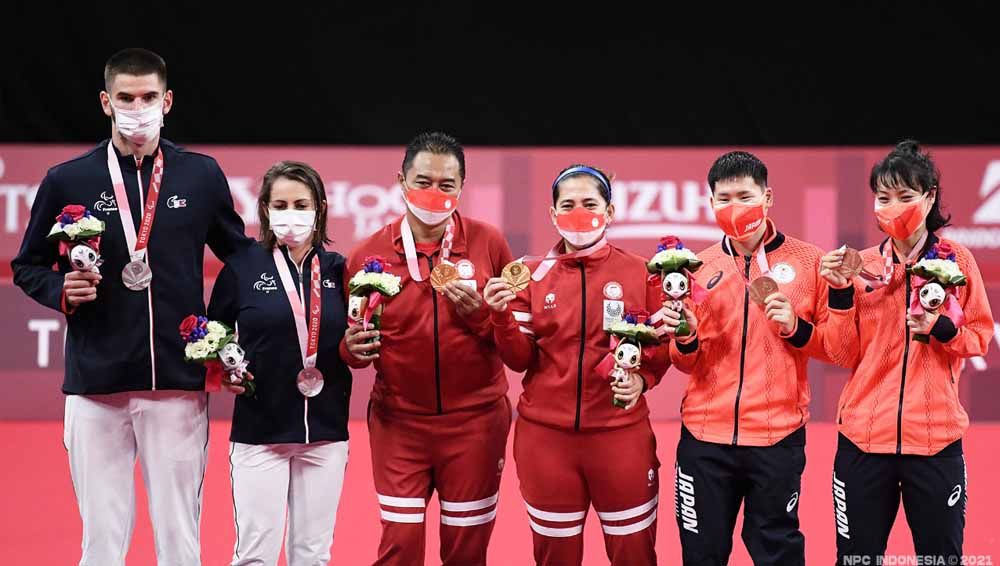 Peraih medali emas, Hary Susanto dan Leani Ratri Oktila, berpose di podium Paralimpiade Tokyo 2020.  Copyright: © NPC Indonesia