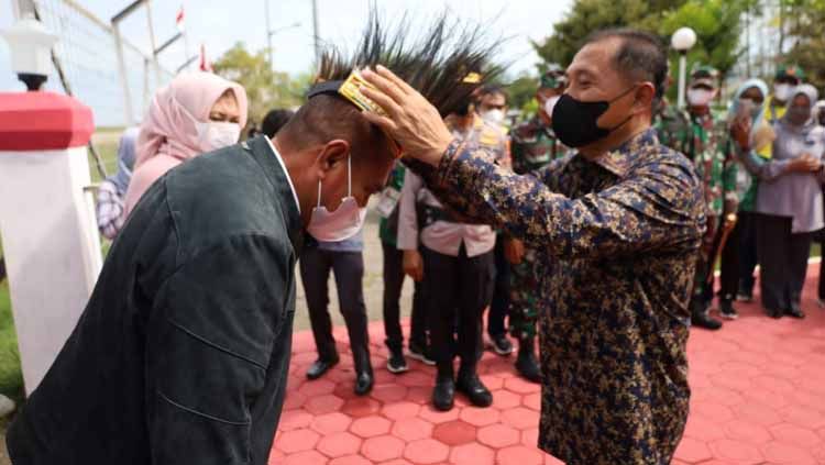 Wakil Bupati Merauke, Riduan, saat menyematkan hiasan kepala kepada Gubernur Sumut, Edy Rahmayadi, saat baru tiba di Merauke. Copyright: © Humas KONI Sumut