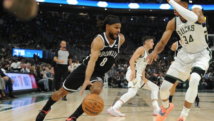 Patty Mills (Nets) mencoba keluar dari hadangan Giannis Antetokounmpo (Bucks) di laga pembuka NBA 2021-2022 (20/10/21). Copyright: © Michael McLoone/REUTERS