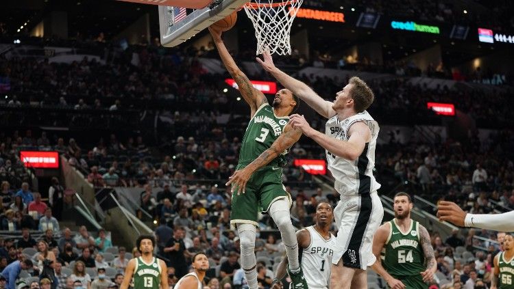 Lay Up George Hill (Buck) yang gagal dihadang Jakob Poeltl (Spurs), Minggu (24/10/21). Copyright: © Daniel Dunn-USA TODAY Sports/REUTERS