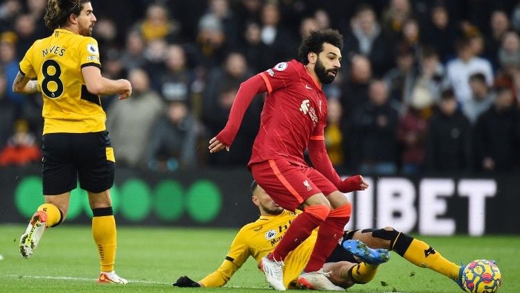 Mohamed Salah berduel dengan Romain Saiss memperebutkan bola di laga Wolves vs Liverpool, Sabtu (04/12/21). Copyright: © REUTERS/Peter Powell