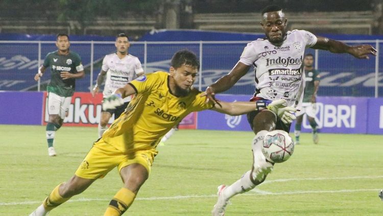 Kiper Tira Persikabo, Dicky Indrayana berusaha menjangkau bola yang direbut penyerang Bali United, Privat Mbarga dalam laga BRI Liga 1 2021/2022 di Stadion Ngurah Rai, Denpasar, Kamis (3/2/22) malam. Foto : Nofik Lukman Hakim/INDOSPORT Copyright: © Nofik Lukman Hakim/INDOSPORT