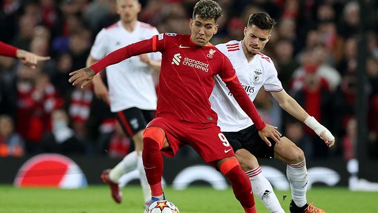 Pemain Liverpool, Roberto Firmino sedang berusaha melindungi bola dari rebutan pemain Benfica di Liga Champions. Copyright: © REUTERS/Phil Noble