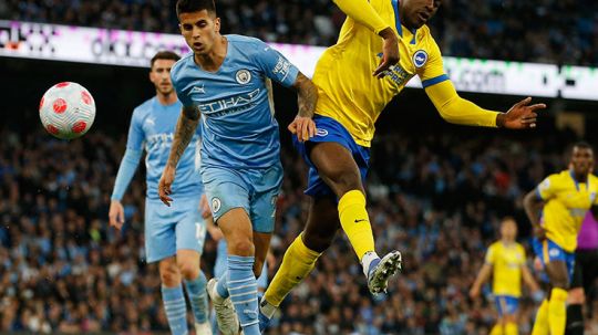 Perebutan bola antara peman Manchester City (Man City), Joao Cancelo dengan pemain Brighton, Danny Welbeck. Copyright: © REUTERS/Craig Brough