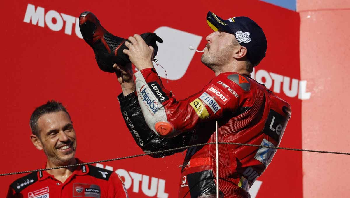 Pembalap Ducati Jack Miller, minum sampanye dari sepatunya saat ia merayakan di podium setelah memenangkan perlombaan. Foto: REUTERS/Issei Kato Copyright: © REUTERS/Issei Kato