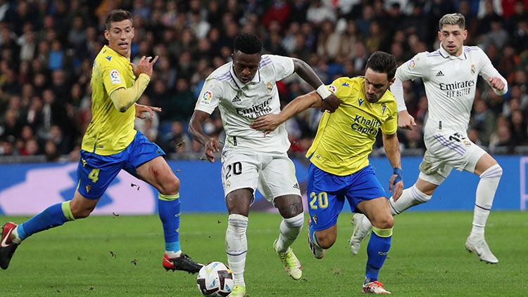 Penyerang Real Madrid, Vinicius Jr berusaha melindungi bola dari rebutan pemain Cadiz di Liga Spanyol. Copyright: © REUTERS/Violeta Santos Moura