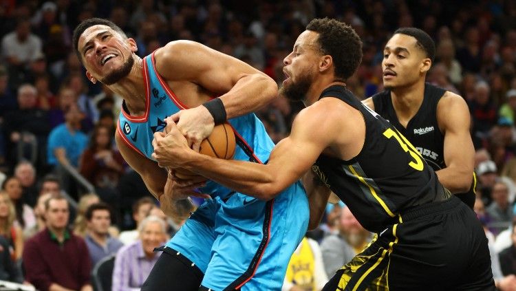 Devin Booker (kiri) berebut bola dengan Stephen Curry di duel Phoenix Suns vs Golden State Warriors (17/11/22). (Foto: Mark J. Rebilas-USA TODAY Sports) Copyright: © Reuters/Mark J. Rebilas-USA TODAY Sports