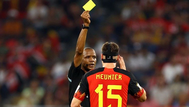 Wasit asal Zambia, Janny Sikazwe, saat memberi kartu kuning ke Thomas Meunier di laga Piala Dunia 2022 Belgia vs Kanada (24/11/22). (Foto: REUTERS/Siphiwe Sibeko). Copyright: © REUTERS/Siphiwe Sibeko