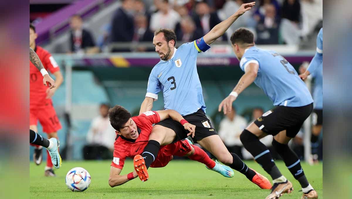 Duel keras pemain Korea Selatan Hwang Ui-jo dengan pemain Uruguay Diego Godin di grup H Piala Dunia Qatar 2022. (Foto: REUTERS/Kim Hong-Ji) Copyright: © REUTERS/Kim Hong-Ji