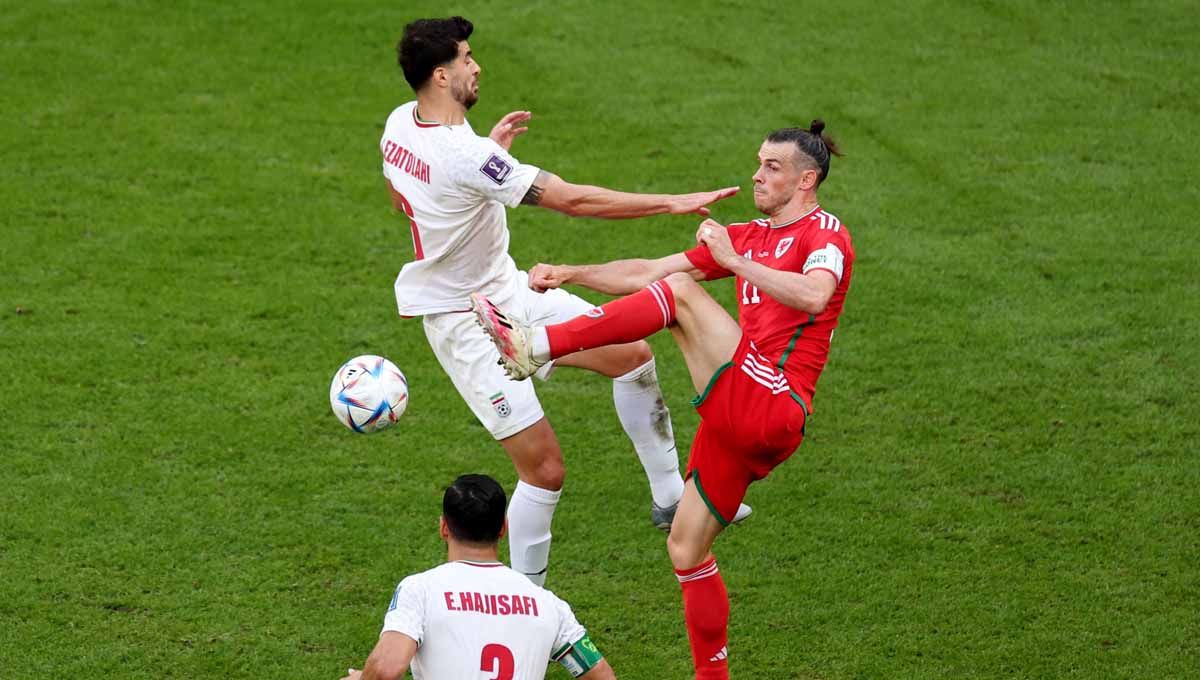 Aksi pemain Wales Gareth Bale berduel dengan pemain Iran Saeid Ezatolahi. (Foto: REUTERS/Marko Djurica) Copyright: © REUTERS/Marko Djurica
