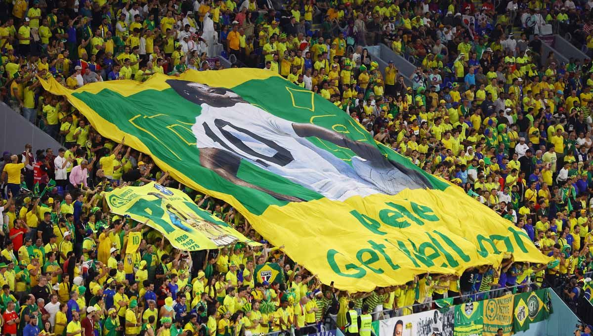 Aksi Fans Brasil mengangkat spanduk mantan pemain Brasil Pele dengan pesan semoga cepat sembuh. (Foto: REUTERS/Paul Childs) Copyright: © REUTERS/Paul Childs
