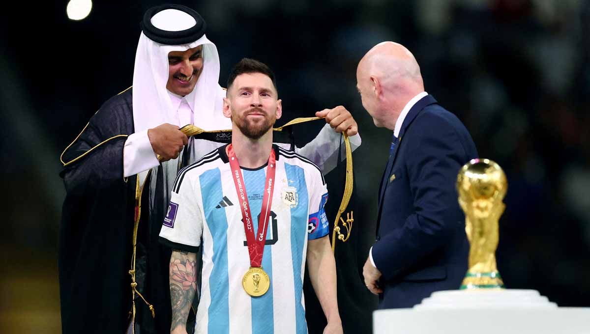 Lionel Messi mendapatkan jubah dari Sheikh Tamim bin Hamad Al Thani dan Presiden FIFA Gianni Infantino saat penyerahan Piala Dunia. (Foto: REUTERS/Hannah Mckay) Copyright: © REUTERS/Hannah Mckay