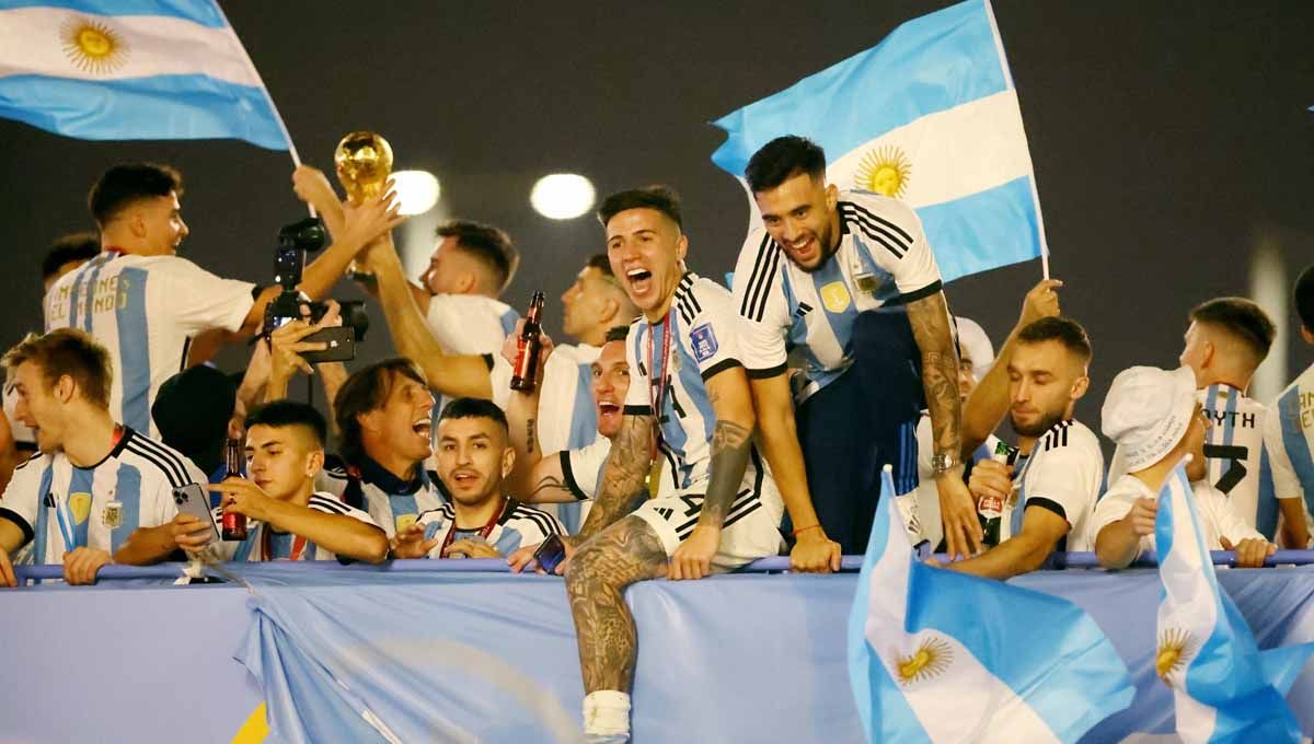 Para pemain Argentina merayakan dengan trofi di luar stadion usai menjuarai Piala Dunia Qatar 2022. (Foto: REUTERS/Hannah Mckay) Copyright: © REUTERS/Hannah Mckay