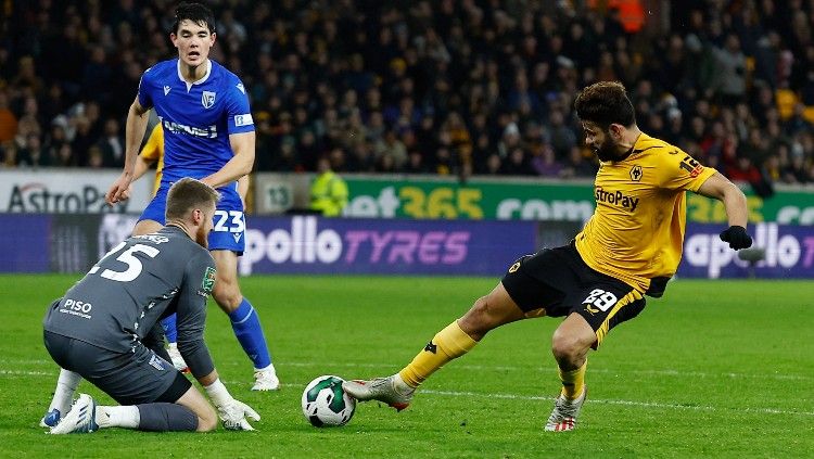 Elkan Baggott (kiri) melihat Diego Costa melepaskan tembakan di laga Wolves vs Gillingham (21/12/22). (Foto: REUTERS/Jason Cairnduff) Copyright: © REUTERS/Jason Cairnduff