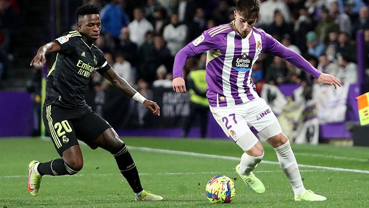 Pemain Real Madrid, Vinicius Jr berusaha merebut bola dari penguasaan pemain Real Valladolid di Liga Spanyol. Copyright: © REUTERS/Violeta Santos Moura