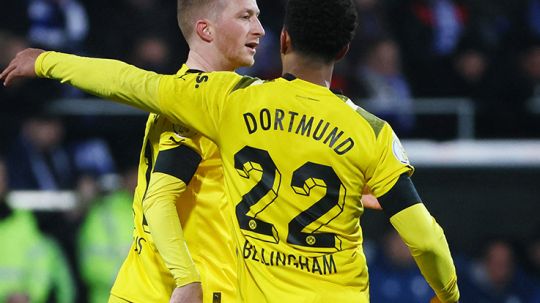 Pemain Borussia Dortmund, Marco Reus dan Jude Bellingham sedang merangkul usai cetak gol. Copyright: © REUTERS/Wolfgang Rattay