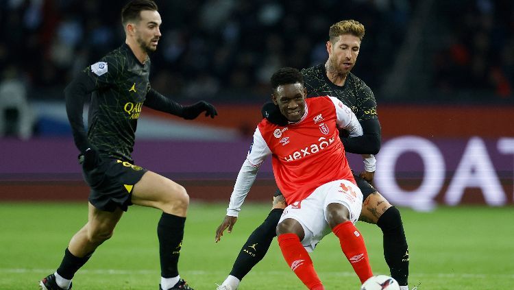 Folarin Balogun (jersey merah) dikawal Sergio Ramos (kanan) dan Fabian Ruiz di laga PSG vs Stade de Reims (30/01/23). Foto: REUTERS/Christian Hartmann. Copyright: © REUTERS/Christian Hartmann