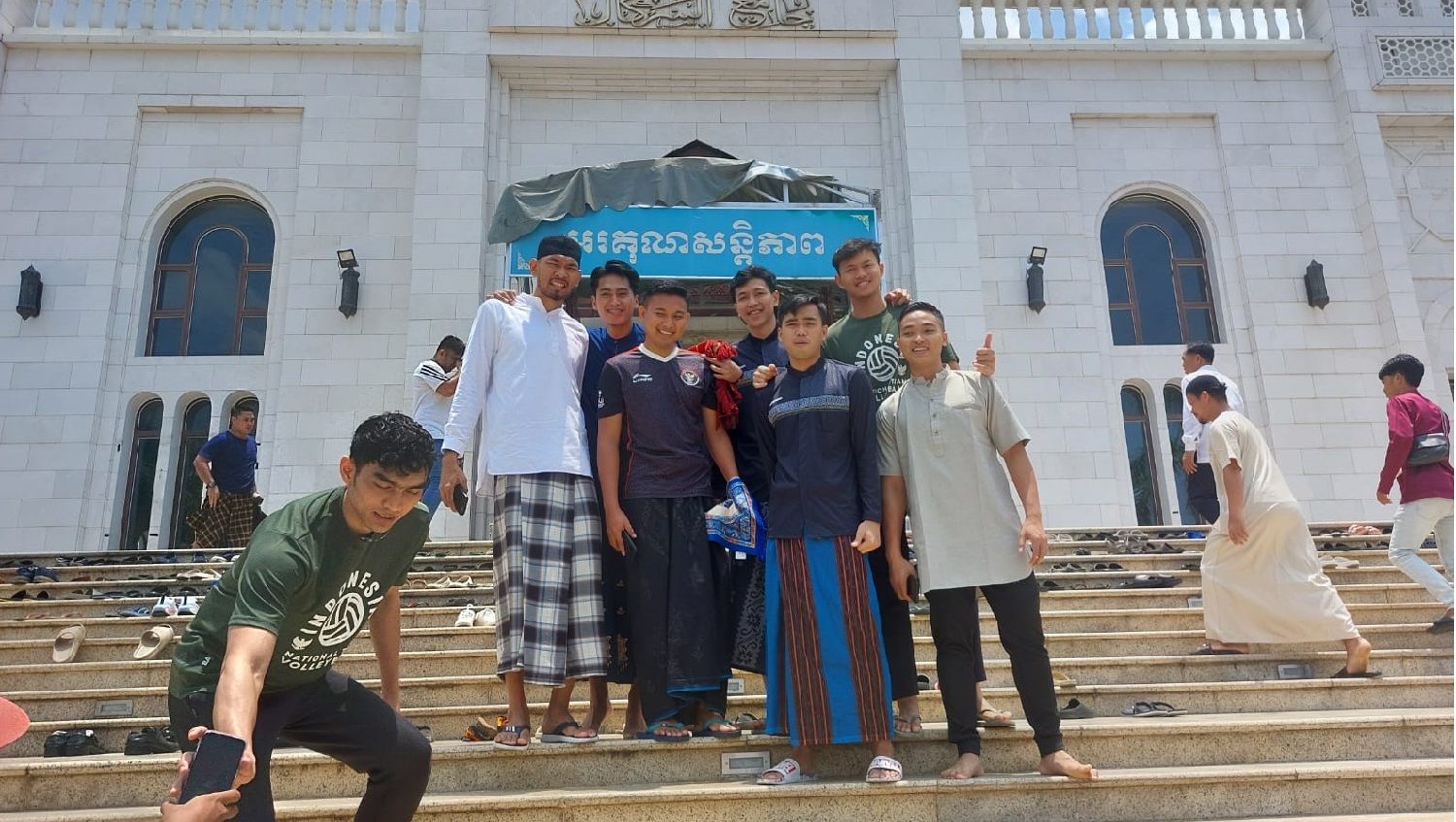 Sejumlah pemain Timnas Indonesia dan fans berfoto di depan Masjid Al Serkal, Kamboja, usai ibadah salat Jumat, Jumat (05/05/23). Copyright: © Zainal Hasan/INDOSPORT