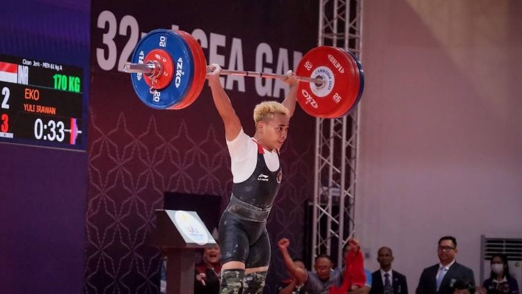 Lifter kebanggaan Indonesia, Eko Yuli Irawan sukses mencetak rekor clean and jerk sekaligus memastikan medali emas dari angkat besi di SEA Games 2023 Kamboja. Copyright: © CdM Indonesia SG 2023 / Evan Andraws