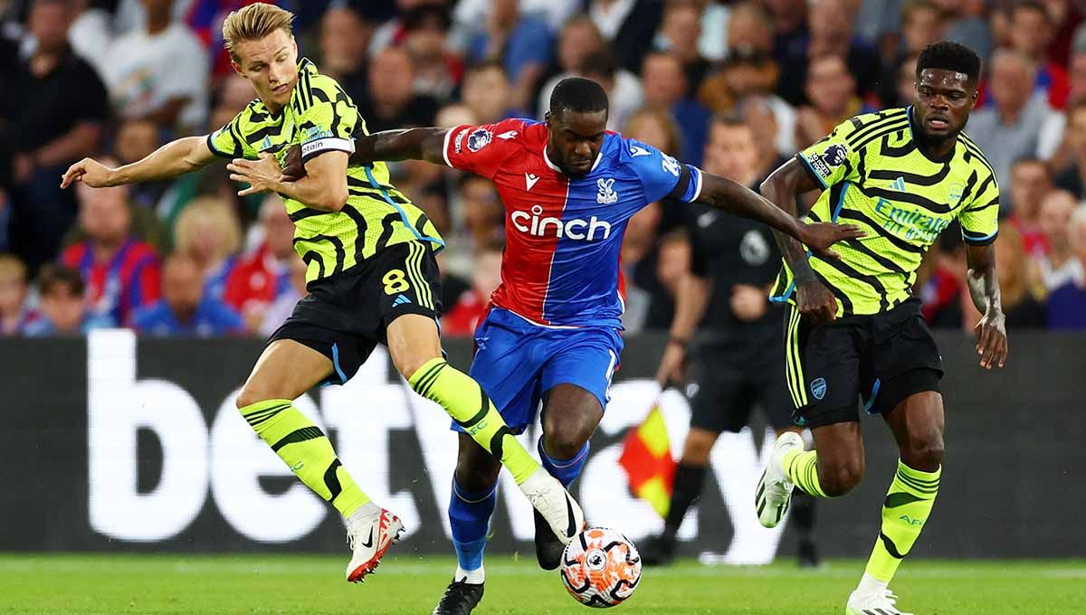 Pemain Arsenal, Martin Odergaard dan Thomas Partey sedang menekan pemain Crystal Palace di Liga Inggris. Copyright: © Reuters/Andrew Boyers