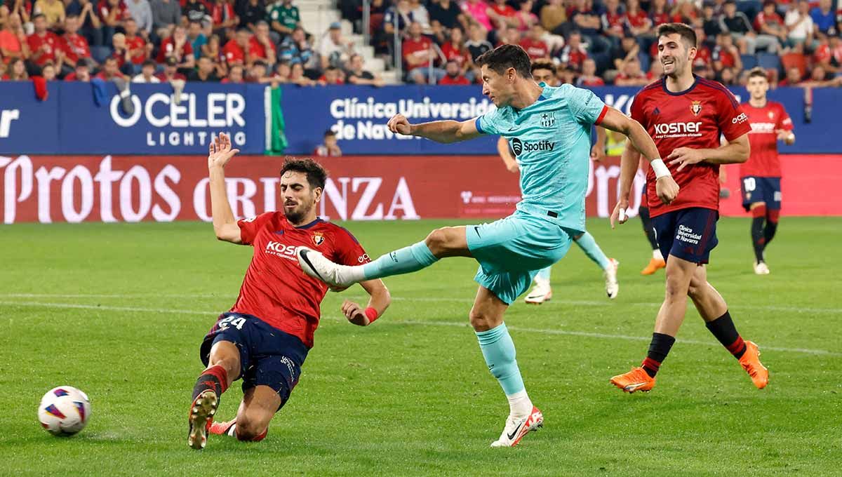Pemain Barcelona, Robert Lewandowski melepaskan tendangan dan coba diadang pemain Osasuna di Liga Spanyol. Copyright: © REUTERS/Vincent West