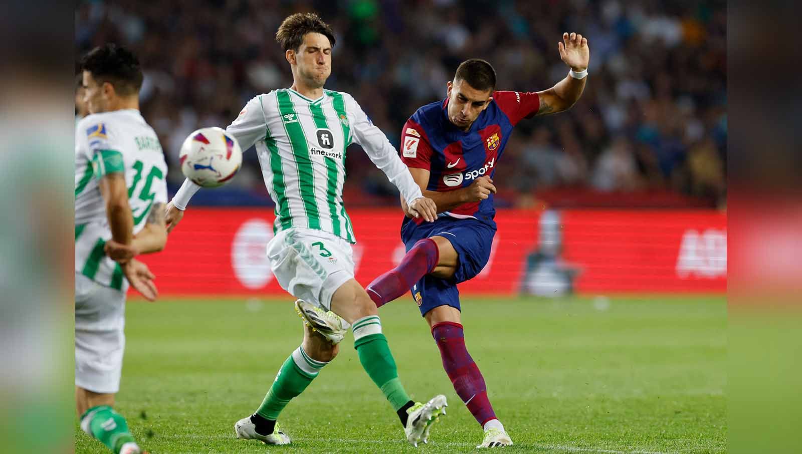 Pemain Real Betis, Juan Miranda berebut bola dengan pemain Barcelona Ferran Torres. (Foto: REUTERS/Albert Gea) Copyright: © REUTERS/Albert Gea