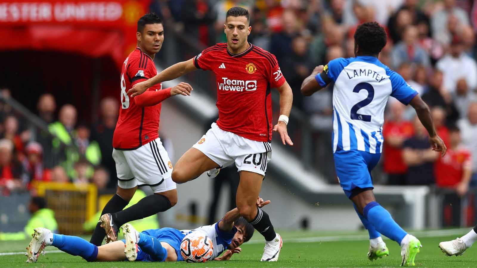 Pemain Brighton & Hove Albion, Kaoru Mitoma terjatuh saat berebut bola dengan pemain Manchester United Diogo Dalot. (Foto: REUTERS/Molly Darlington) Copyright: © REUTERS/Molly Darlington