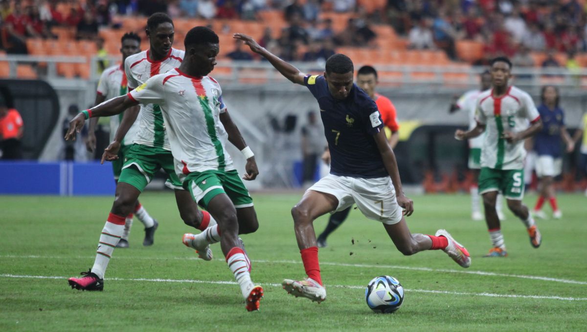 Pemain Prancis, Yanis Issoufou saat mencoba melewati hadangan pemain Burkina Faso pada laga fase grup E di Stadion JIS, Minggu (12/11/23). Copyright: © Herry Ibrahim/INDOSPORT