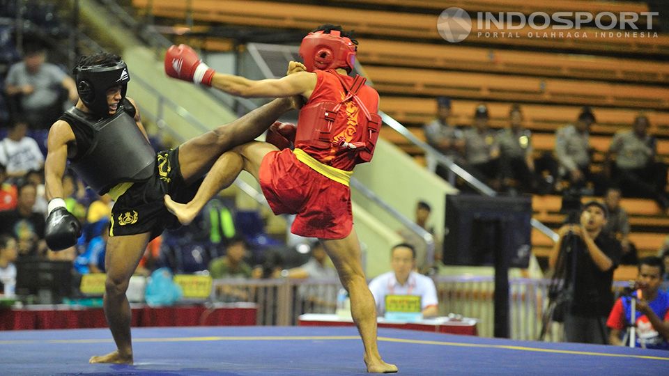 Huong Dinh Van (baju hitam) melancarkan tendangan ke arah kepala atlet wushu Indonesia Edowar Virnanda (merah) pada kelas 52 kg Kejuaraan Sanda Wushu VII 2014 di Istora Senayan, Jakarta, Kamis (20/11/14). Copyright: © Ratno Prasetyo/INDOSPORT